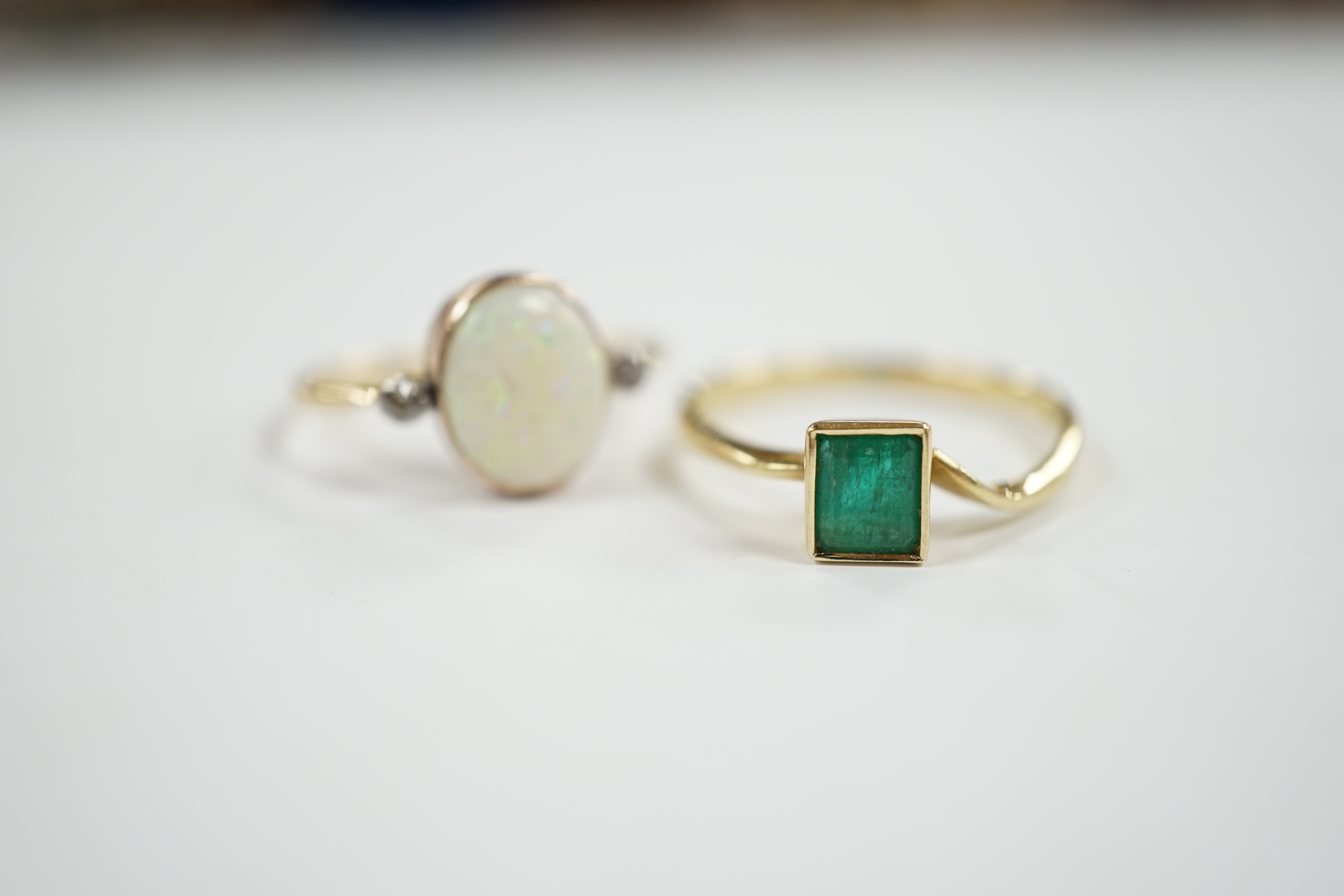 An 18ct & plat, white opal and two stone diamond set ring, size O and an 18k and single stone emerald ring, gross weight 4.1 grams.